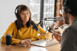 Man and woman podcasters interview each other for radio podcast in studio.