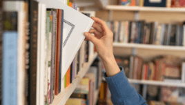 Female hand pulling book from bookshelf