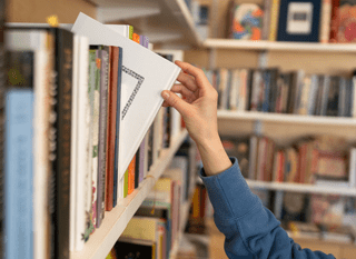 Female hand pulling book from bookshelf