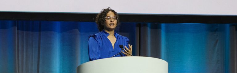 African American woman at podium presenting on stage at the meeting