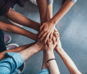 Close up top view of young people putting their hands together.